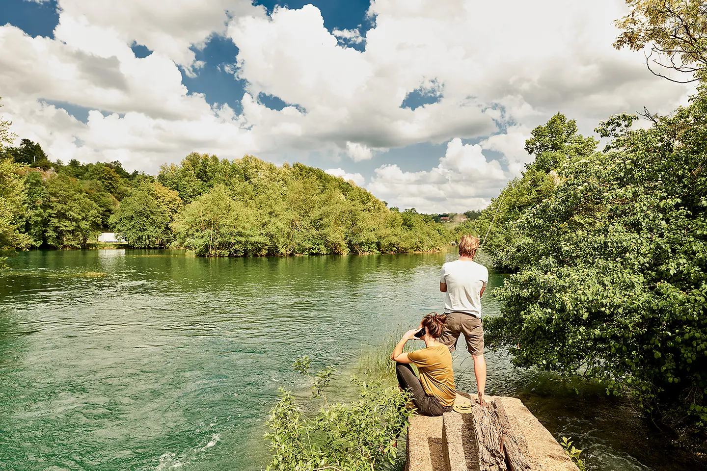 A couple is fishing by a lake